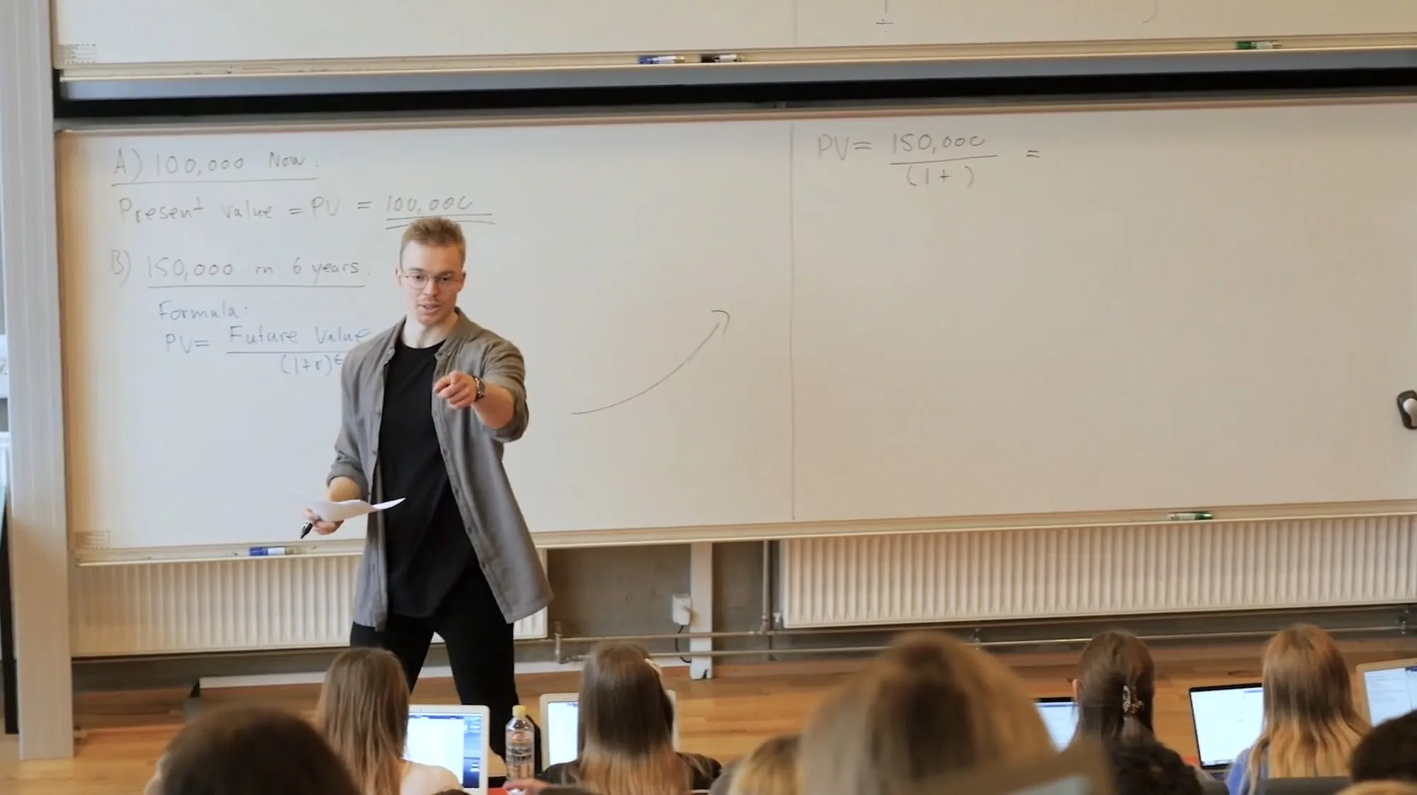 Kim teaching a finance lecture, pointing at a student